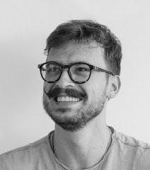 Portrait d'un homme souriant portant des lunettes, représentant le style urbain et moderne.