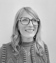 Portrait d'une femme souriante portant des lunettes, en noir et blanc, représentant la diversité et.